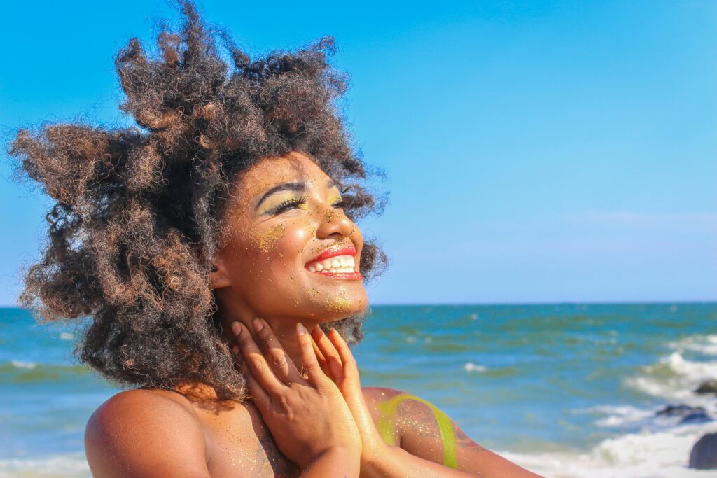 A radiant woman with glowing skin, enjoying sunlight at the beach.