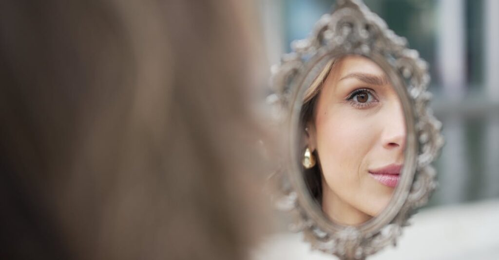 A close-up of a woman’s face reflecting in an ornate mirror, showcasing smooth, radiant, and flawless skin.