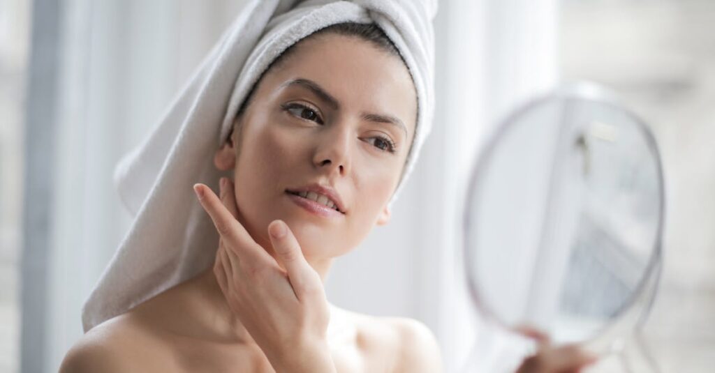 A woman examining her face in a mirror, gently touching her skin to check for fine lines and wrinkles.enhancing her natural beauty in the comfort of her home.