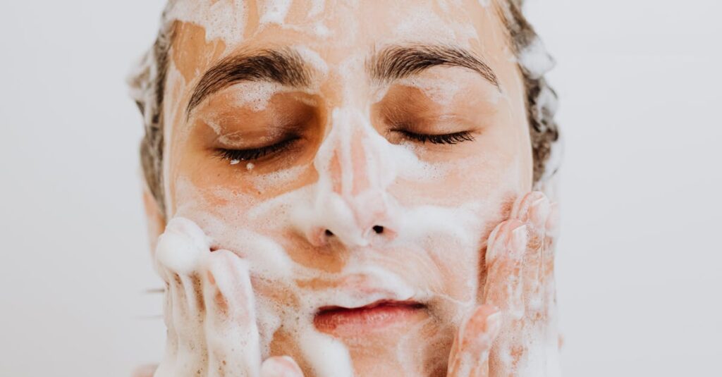 Woman cleansing her face with detoxifying skincare products to achieve radiant skin.