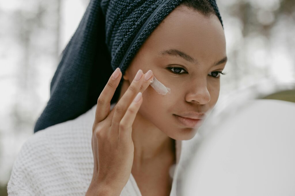 A woman applying cream to her cheek, focusing on skincare and scar treatment.