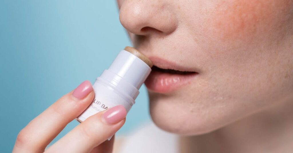 Close-up of someone applying SPF lip balm to prevent cold sores.