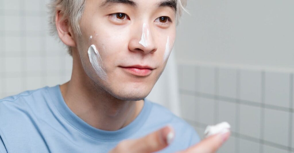 Man’s hand applying hydrating cream to his face after shaving.