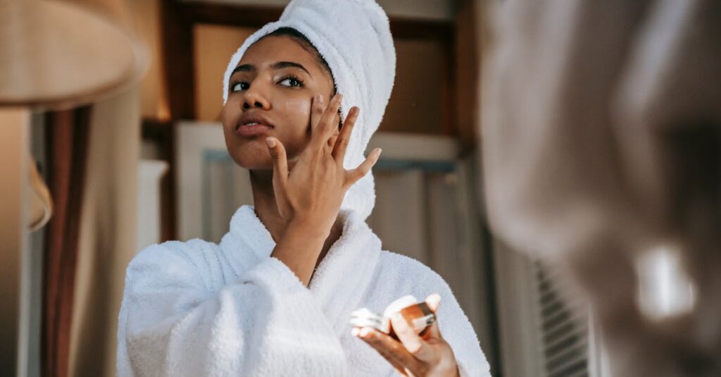 A woman in a white bathrobe applying moisturizer to her cheek, highlighting a skincare routine for sensitive skin.