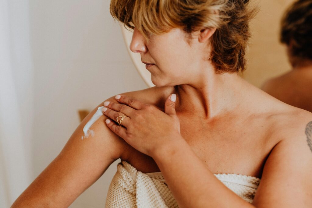 A woman applying arm firming serum on her upper arm to improve skin elasticity and tone.