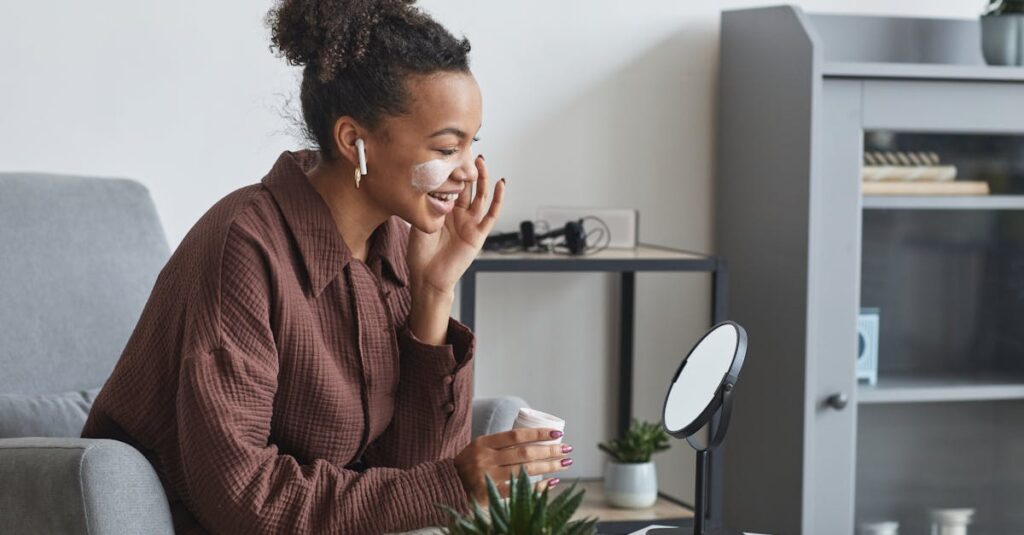 A smiling woman applying skincare cream while sitting indoors, protecting her skin from spring allergies.