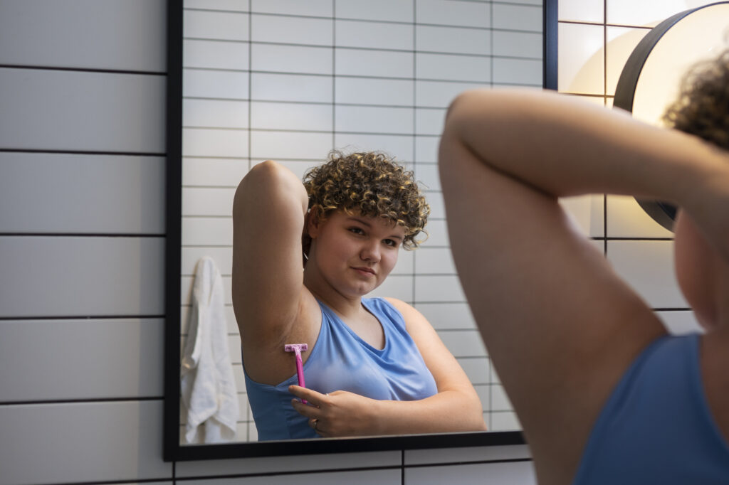 A close-up of a women shaving her under arms.